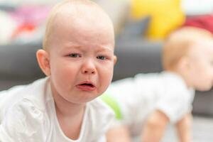 wenig unzufrieden Kind Weinen auf das Fußboden im seine Zimmer foto