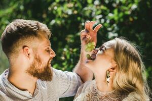 glücklich Paar verbringen Zeit zusammen und Futter jeder andere Trauben im Sommer- draußen foto