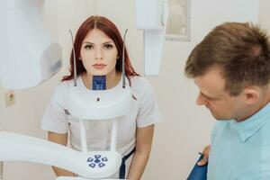 ein Mädchen geduldig macht ein Panorama- Röntgen von das Oral Hohlraum auf ein orthopantomographisch Gerät, und das Zahnarzt nimmt ein Bild foto