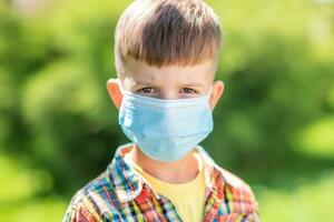 Porträt von ein wenig Junge im ein schützend Maske auf das Straße während das Coronavirus und covid Pandemie - - 19 foto