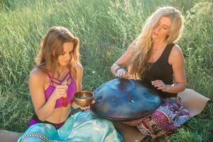 jung Frauen abspielen und singen auf das Musical Instrument Handpan. trainieren Meditation beim Sonnenuntergang foto