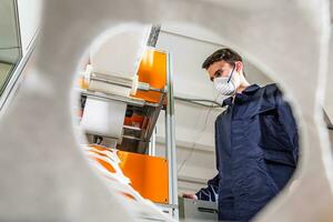 ein Arbeiter steht beim das Maschine im ein Fabrik zum das Herstellung von medizinisch Masken mit Nanofaser. Coronovirus und covid-19 Schutz foto