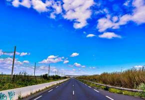 ein lange leeren Straße mit Blau Himmel und Wolken foto