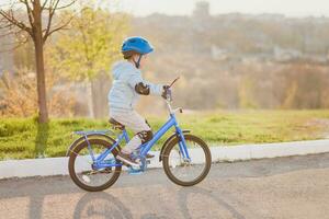 wenig Kind im Helm Fahrten ein Fahrrad auf ein sonnig Tag foto