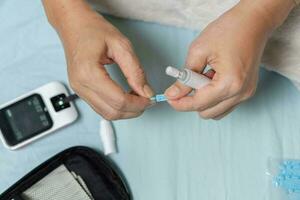 ein Frau Hand Überprüfung ihr Blut Zucker Niveau mit ein Glukometer durch Sie selber beim ihr heim. ShotlistGesundheit foto