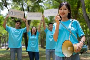 glücklich jung asiatisch Studenten vielfältig Freiwillige halt ein Kampagne Zeichen zum Reinigung im das Park, das Konzept von Umwelt Erhaltung auf Welt Umgebung Tag, Recycling, Nächstenliebe zum Nachhaltigkeit. foto