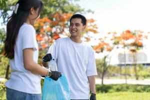 glücklich jung asiatisch Studenten vielfältig Freiwillige mit Müll Taschen Reinigung Bereich im das Park, das Konzept von Umwelt Erhaltung auf Welt Umgebung Tag, Recycling, Nächstenliebe zum Nachhaltigkeit. foto