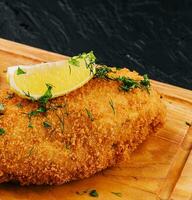 paniert Schnitzel auf ein Schneiden Tafel foto