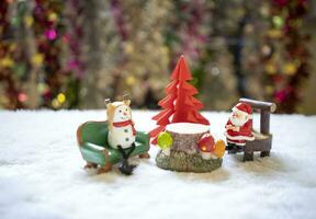 sata Sitzung auf hölzern Stuhl mit Schneemann Sitzung auf Grün Sofa reden zu Weihnachten im Vorderseite von rot Origami Weihnachten Baum warten zum komisch Festival, Weihnachten und Neu Jahr Konzept. foto