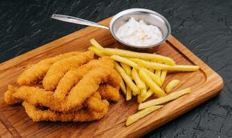 Hähnchen Nuggets und Französisch Fritten auf hölzern Tafel foto