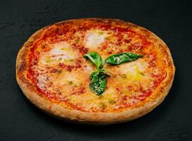 Margherita Pizza mit Basilikum auf schwarz Stein foto