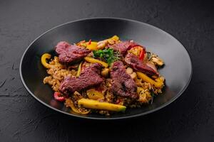 Chinesisch gebraten Reis mit Rindfleisch auf schwarz Teller foto