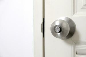 rostfrei Stahl Tür Knopf oder das Griff auf das hölzern Tür im ein hell zündete Zimmer. Konzept von Sauberkeit und Hygiene. foto