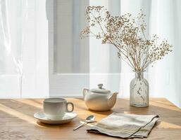 ein Tasse von Tee, Teekanne und trocken Strauß Blumen auf das hölzern Tabelle von ein Fenster mit Morgen Sonnenlicht. foto