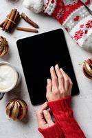 Weihnachtsdesktop mit Tablet, umgeben von Kaffee, Strümpfen