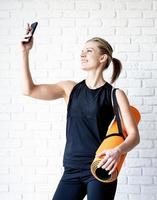 junge lächelnde Fitnessfrau macht Selfie nach dem Training foto