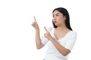 jung asiatisch schön Frau im schwarz lange Haar trägt Weiß Hemd und zeigt an Punkt oben zu Geschenk etwas während isoliert auf Weiß Hintergrund. foto