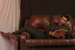 ein Mann Sitzung auf ein braun Leder Couch foto