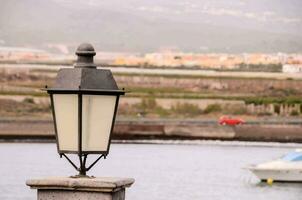 ein Lampe Post in der Nähe von das Wasser mit ein Boot im das Hintergrund foto