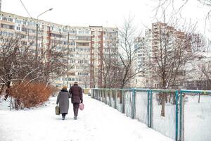 ein alt Mann und ein alt Frau gehen entlang das Schulhof im Winter im ein Wohn Bereich von das Stadt foto