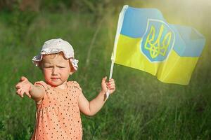 wenig traurig Mädchen hält winken Flagge von Ukraine. Kind Bedürfnisse Hilfe und erreicht aus. foto