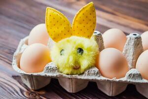 ein klein flauschige Hase Nächster zu das Eier im das Ei Tablett zum das Ostern Urlaub foto