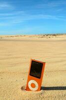ein Orange Musik- Spieler Sitzung im das Sand foto