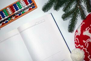 Weihnachten leeren Notizbuch, Tagebuch zum Brief zu Santa oder Ihre Wunschzettel oder Advent Aktivitäten auf Weiß. mental Arithmetik Partituren Abakus Nächster zu Neu Jahre Hut und Fichte Geäst foto