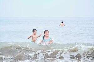 ein Junge und ein Mädchen sind haben Spaß spielen im das Meer. foto