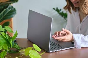 Damen Hände beim ein Laptop gegen ein Hintergrund von Grün. foto