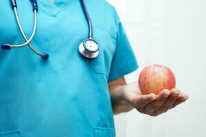 asiatisch Ernährungsberater halten Apfel gesund Essen zum geduldig im Krankenhaus, Ernährung und Vitamin. foto