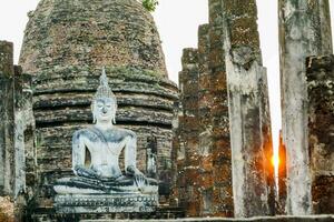 ein Buddha Statue sitzt auf oben von ein Backstein Mauer foto