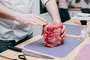 Kochen Fleisch Rollen im das Kochen Klasse. Rindfleisch rollen. roh Fleisch, Nahaufnahme, Hände im das rahmen. foto