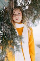 Teen blond im ein Gelb Sweatshirt draußen im Winter. ein Teenager Mädchen auf ein gehen im Winter Kleider im ein schneebedeckt Wald foto