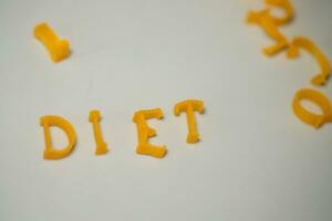 Wort Diät besteht von essbar Briefe. Pasta Diät Lebensmittel. Pasta im bilden von Briefe auf grau Hintergrund. richtig Ernährung Konzept. foto