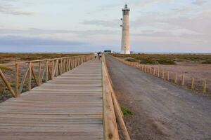 ein hölzern Gehweg führt zu ein Leuchtturm im das Mitte von das Wüste foto