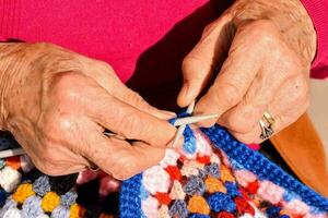 ein älter Frau ist Stricken ein bunt häkeln Decke foto