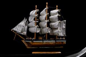 ein Modell- von ein Segeln Schiff auf ein schwarz Hintergrund foto