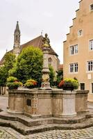 ein Brunnen im das Center von ein Stadt, Dorf mit Gebäude auf entweder Seite foto