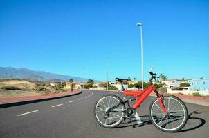 ein rot Fahrrad ist geparkt auf das Seite von das Straße foto