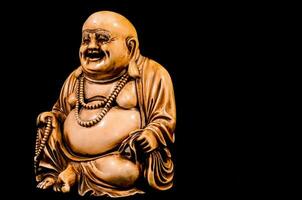 ein Statue von ein Lachen Buddha Sitzung auf ein schwarz Hintergrund foto