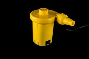 ein Gelb Plastik Pumpe auf ein schwarz Hintergrund foto