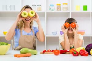 glücklich Mutter und ihr Tochter haben Spaß während Sie sind Herstellung gesund Mahlzeit zusammen beim ihr heim. foto