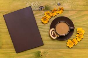 Bild von Tasse von Kaffee, Plätzchen und Buch mit schön Blumen auf hölzern Hintergrund foto