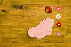 wenig Rosa Baby Mädchen Socken mit Schnuller und Blumen auf hölzern Tisch.Baby Ankündigung Konzept. foto