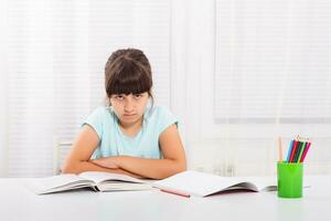 wütend wenig Mädchen Muss bleibe beim Zuhause und tun ihr Hausaufgaben, aber sie würde lieber abspielen außen. foto