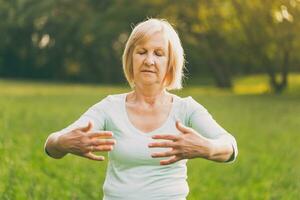 Senior Frau genießt Übung tai Chi im das Natur foto