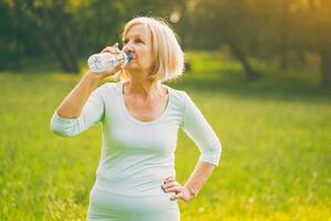 aktiv Senior Frau Trinken Wasser während Übung foto