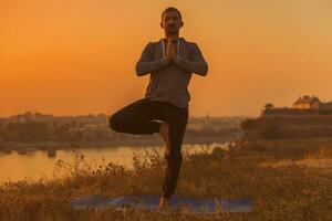 Mann tun Yoga auf Sonnenuntergang mit Stadt Aussicht foto