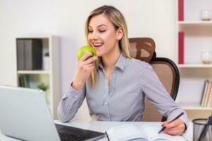 Geschäftsfrau Essen Apfel während Arbeiten im ihr Büro foto